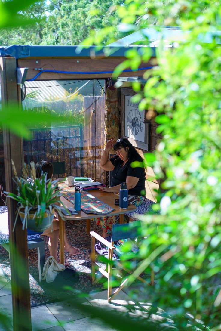 Janine working with a client at a table in the garden studio