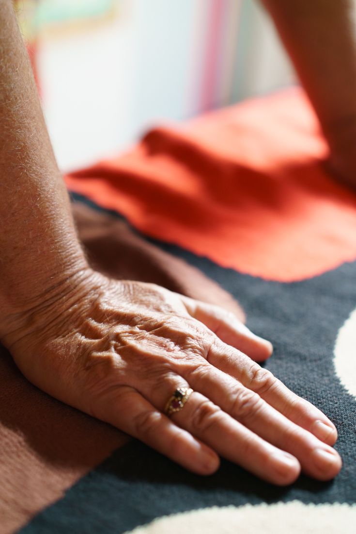 A hand resting on a colourful blanket