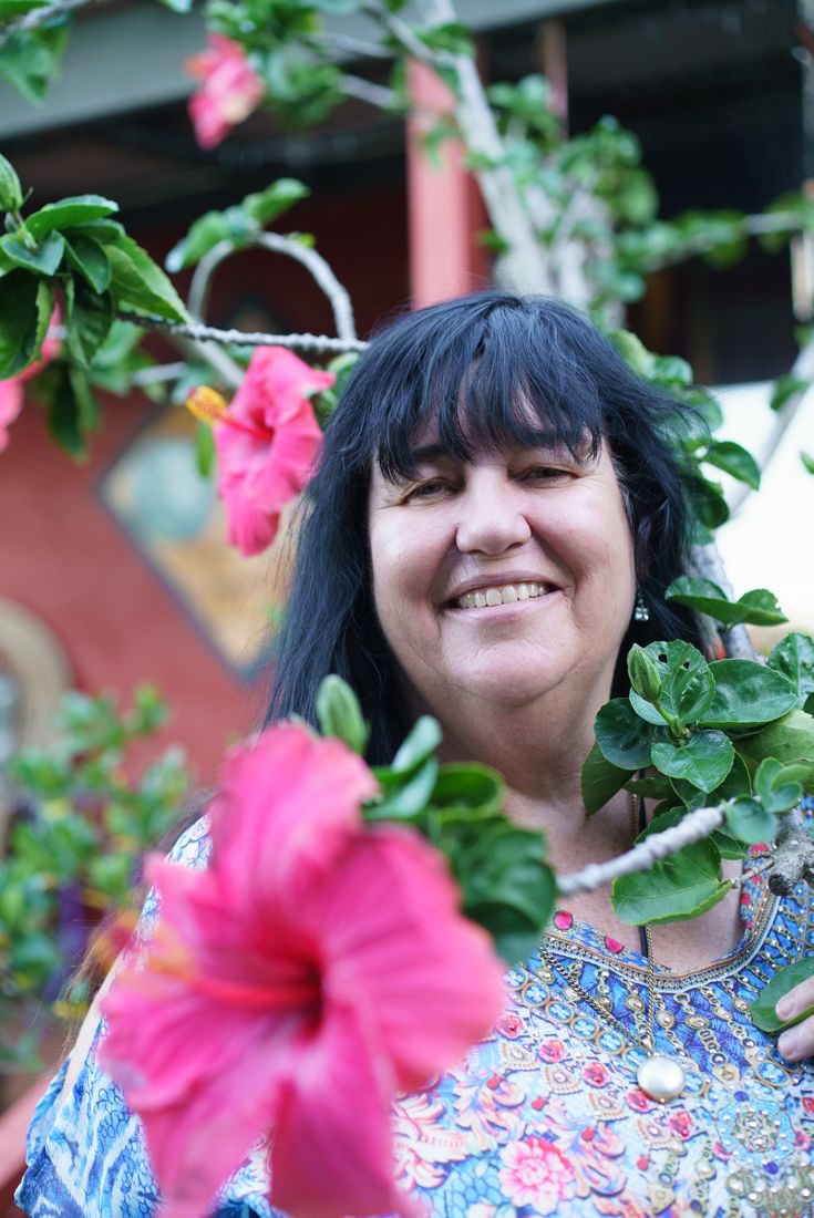 Janine smiling among pink hibiscus flowers