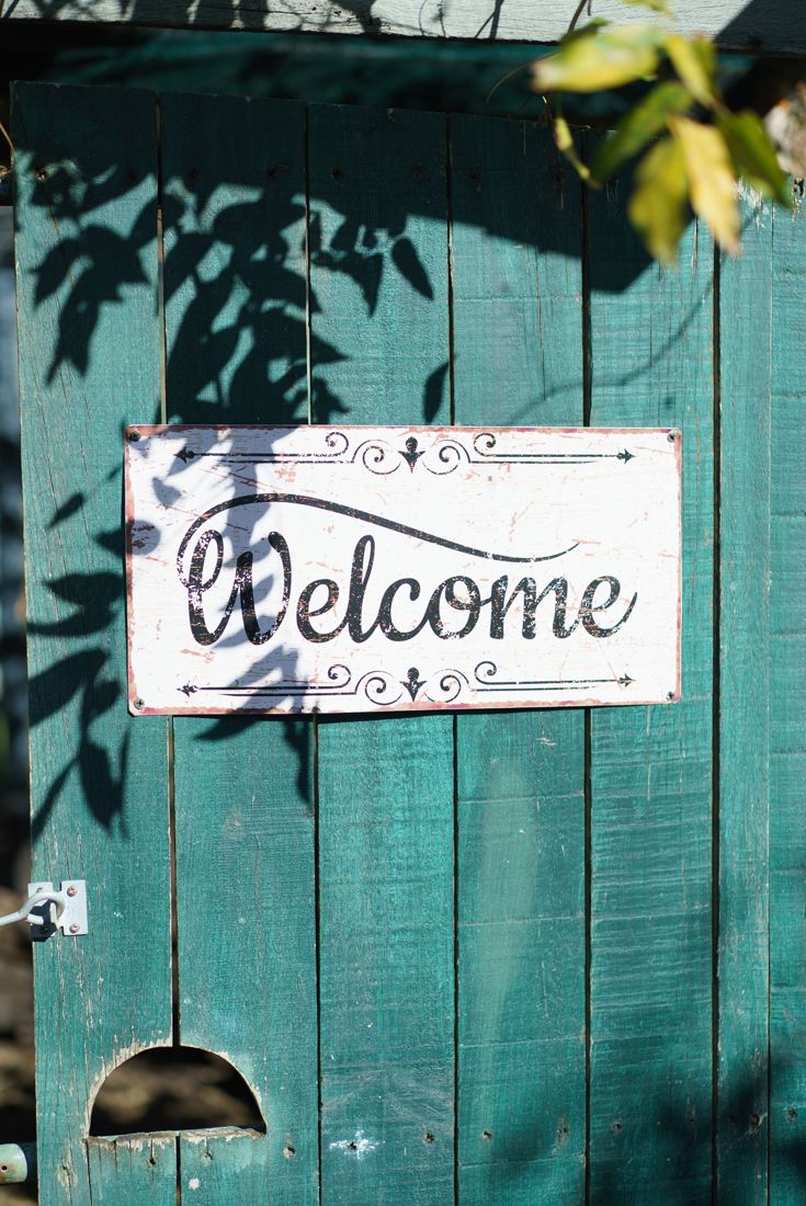 A welcome sign on a green wooden gate